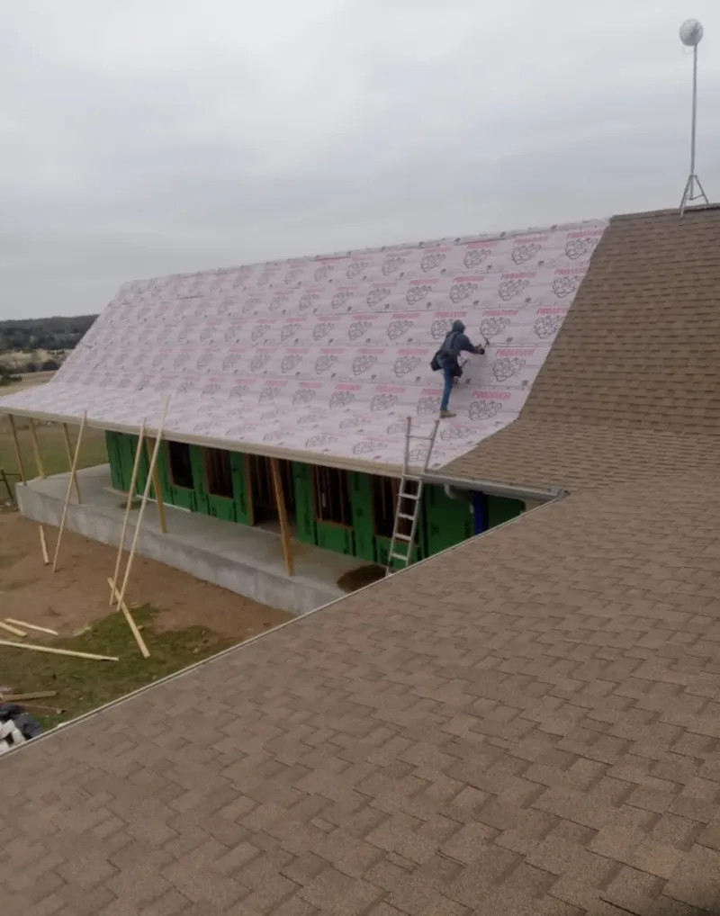 Worker preparing underlayment for a metal roof installation in Westminster